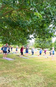 men and women exercising on Pilates mats outdoors